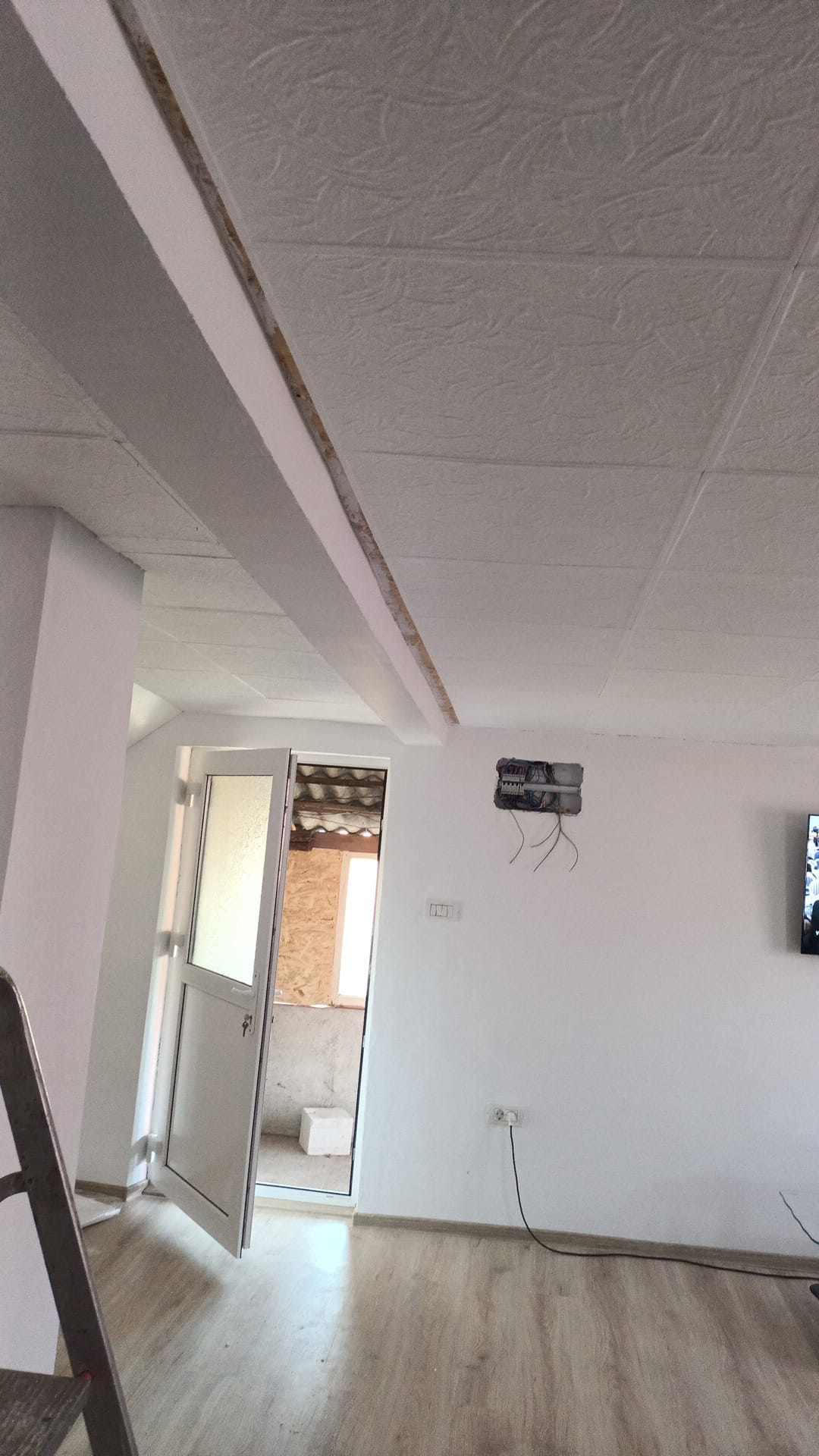 Afgewerkte woonruimte met plafondpanelen, deur en parketvloer