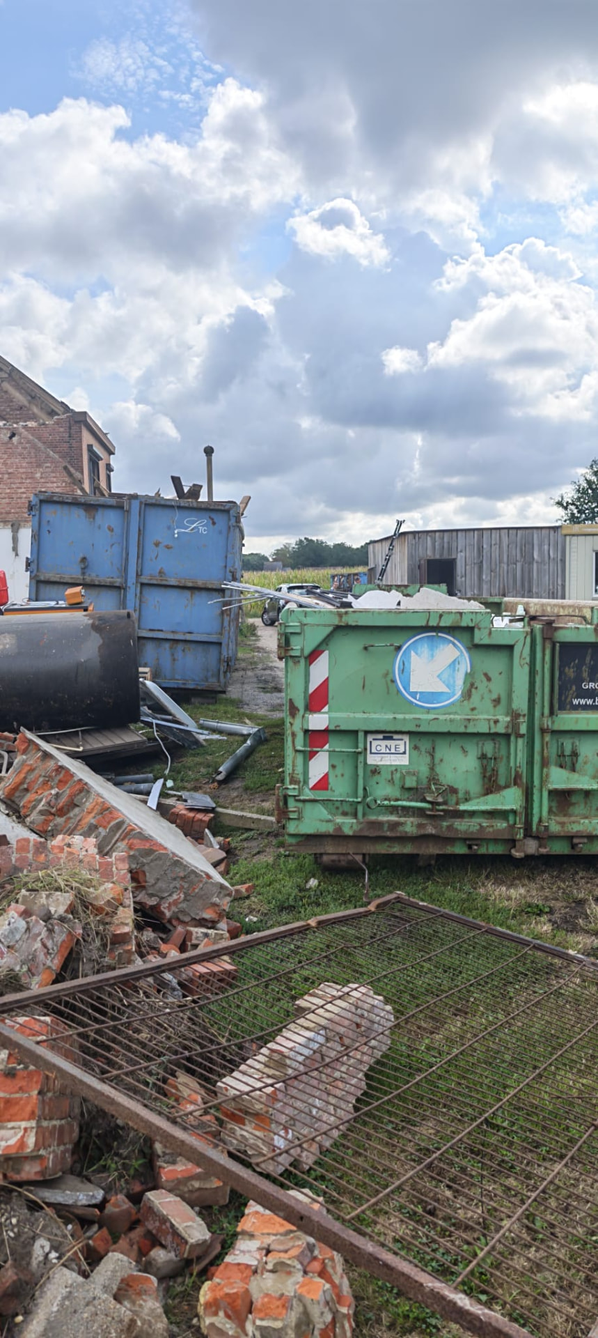 Groene en blauwe afvalcontainers met gescheiden puin en hout