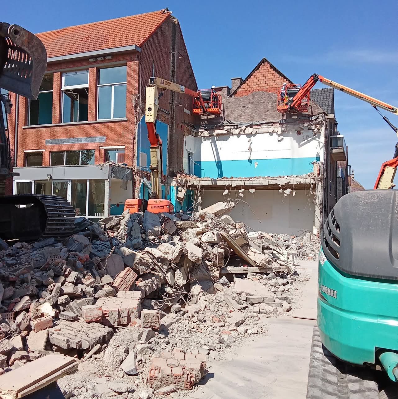 Afbraak van een bakstenen gebouw met hoogwerkers en graafmachines